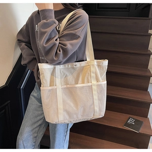 Detalle de bolso tote de lona grande con bolsillos de malla y correas anchas de hombro