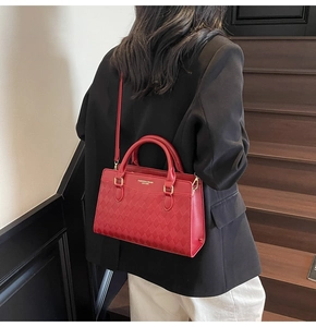 Detail of red quilted leather handbag featuring gold buckles and elegant top handle