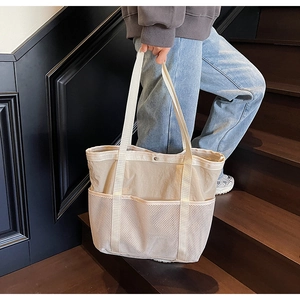 Detalle de un bolso tote grande con bolsillos de malla en escalera de madera