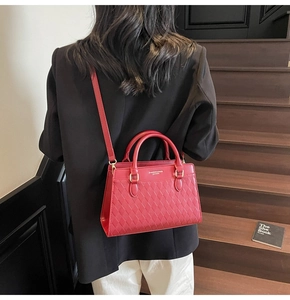 Detail of red quilted leather tote bag featuring gold lettering and long shoulder strap