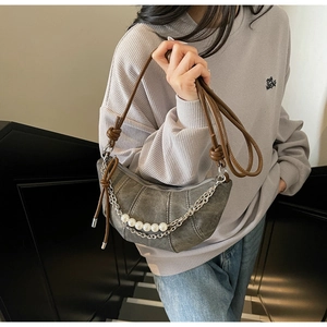Detail view of a retro grey half-moon bag featuring pearl chain and knotted strap details