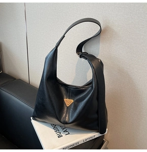 Detail of black matte PU tote bag featuring a golden triangle plaque and adjustable strap