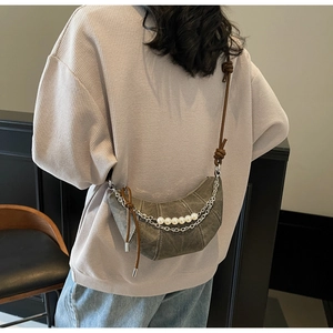 Detail of crescent crossbody bag with double metal chains and large white pearls decoration