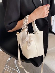 Elegant cream leather bucket bag with silk scarf handle and adjustable strap