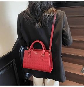 Close-up of red leather wedding tote bag with gold hardware and elegant woven texture