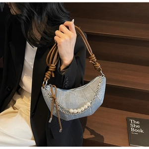 Detail of light blue denim crescent bag with pearl chain and brown leather strap