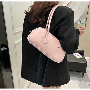 Detail of a pink leather underarm bag with long double straps on a model in a black blazer