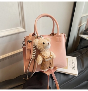 Detail of pink faux leather bucket bag with silver hardware and cute teddy bear charm