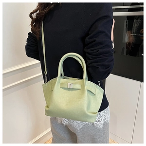 Close-up of pistachio green leather bucket bag with pebble texture and adjustable strap