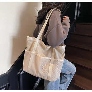 Detalle del bolso de lona beige con bolsillos de malla y gran capacidad de almacenaje