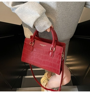 Close-up of red crocodile pattern leather handbag with gold embossed logo text