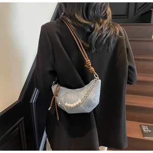 Chic light blue denim crescent bag with pearl chain detail and knotted brown leather strap