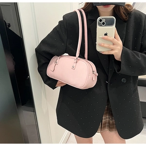 Pink baguette shoulder bag detail showing the sleek leather texture and elongated handles