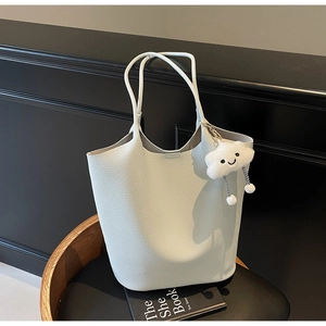 Detail of lychee pattern beige bucket bag with cute cloud charm on leather seat