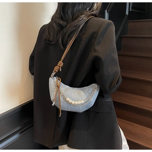 Detail of light blue denim crescent bag with pearl chain and brown knotted leather strap