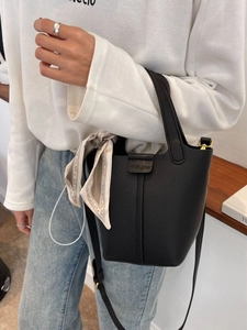 Elegant black lychee grain leather bucket bag with silk scarf on a fashion model