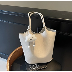 Macro detail of white lychee-textured tote bag featuring a cute cloud plush charm