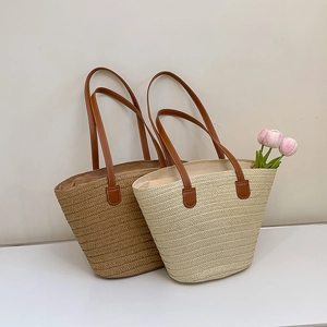Close-up of woven straw tote bag with brown leather handles and natural fiber texture
