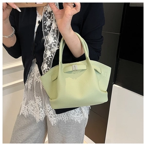Detail of light green pebble leather handbag featuring a silver clasp and wing-shaped design