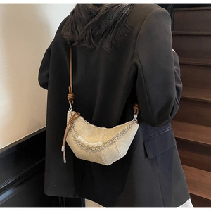 Detail of beige crescent bag with faux leather pleats and elegant pearl chain
