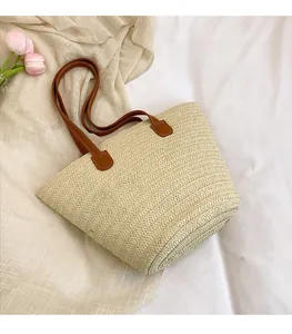 Detail of handwoven beige straw tote texture with brown faux leather shoulder straps