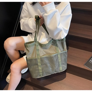 Detalle del bolso tote de lona verde oscuro con bolsillo lateral de malla para guardar