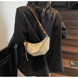 Detail of beige crescent bag with decorative pearl chain and brown leather strap