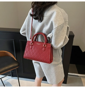 Detail view of dark red quilted leather tote bag with gold hardware and shoulder strap