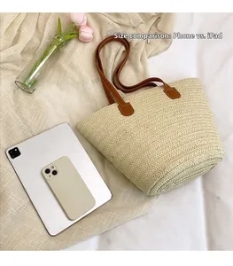 Straw tote bag showing interior storage capacity for iPad and phone on a beige cloth