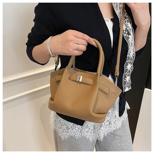 Detail of khaki leather bucket bag with top handle, crossbody strap, and litchi texture