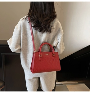 Rear view of a model wearing a red quilted crossbody bag with dual circular handles