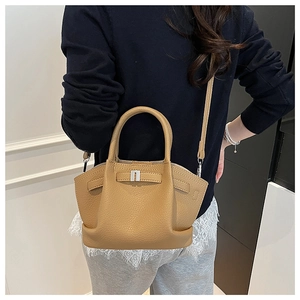Detail of khaki lychee leather bucket bag with silver buckle worn by a model