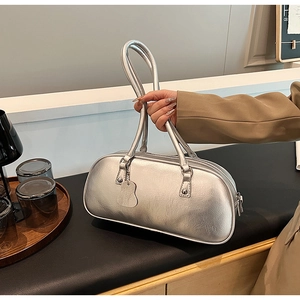 Detail of silver metallic handbag with long handles shown held by a model
