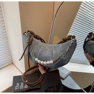Detail of light blue denim crescent bag with silver chain, pearls and knotted leather strap
