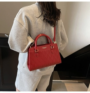 Detail of red quilted leather tote bag with round handles shown on a shoulder strap
