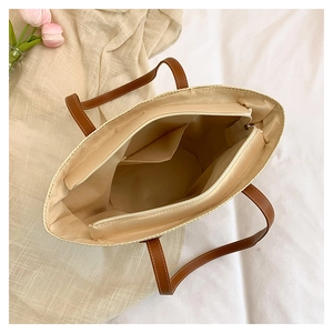 Detailed interior of woven straw tote bag showing zipper pocket and spacious fabric lining
