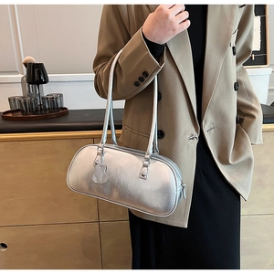 Silver metallic baguette shoulder bag with heart charm shown on model in casual suit