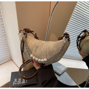 Close-up of beige canvas croissant bag featuring pearl metal chains and leather strap