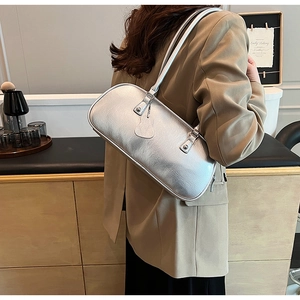 Detailed close-up of a silver underarm bag with retro texture on a khaki blazer
