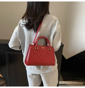 Macro view of red leather tote with diamond quilting and gold fashion logo