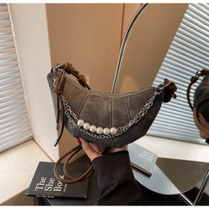 Close-up of grey denim crescent bag featuring pearl chain detail and contrast stitching