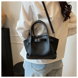 Detailed texture of black lychee grain leather on a stylish bucket bag with shoulder strap