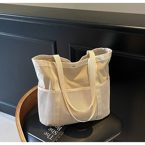 Detalle de bolso tote de lona blanco marfil con bolsillo de malla y correa reforzada