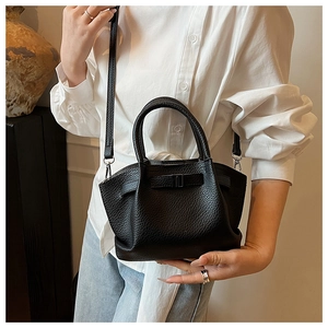 Detail shot of black litchi texture bucket bag with metal buckle and slim shoulder strap