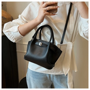 Detail of black litchi leather bucket bag featuring silver buckle and top handle