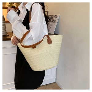 Detail view of woven straw tote bag with dual brown leather handles for beach vacation style