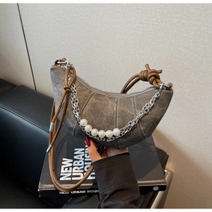 Close-up of grey denim crescent bag with silver chain and white pearl decorations