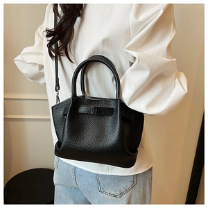 Close-up of black litchi pattern leather texture on a stylish bucket handbag for women