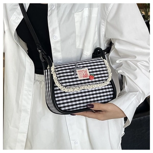 Close-up of contrast checkered canvas crossbody bag with delicate lace trim and cartoon patch