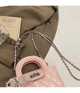 Detail of pink patent leather bag featuring quilted pattern and pearl bow charm